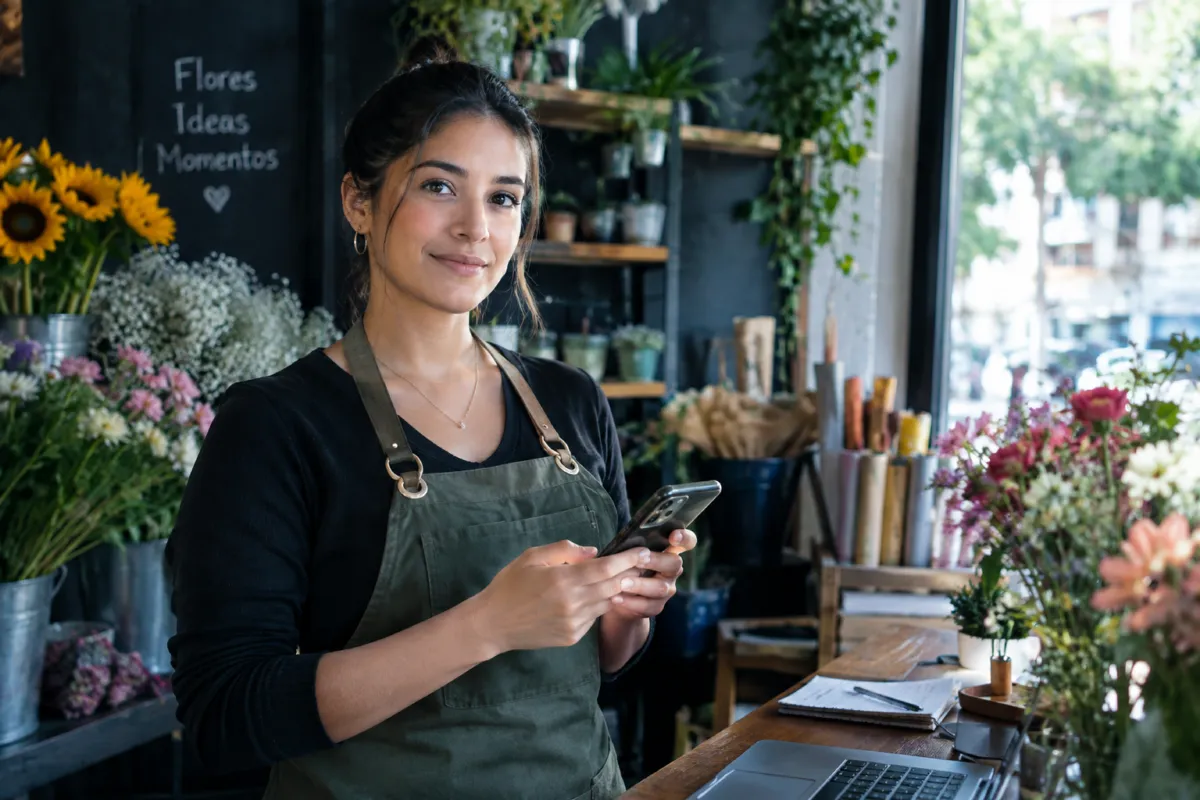 A florist smiling with her phone in her shop
